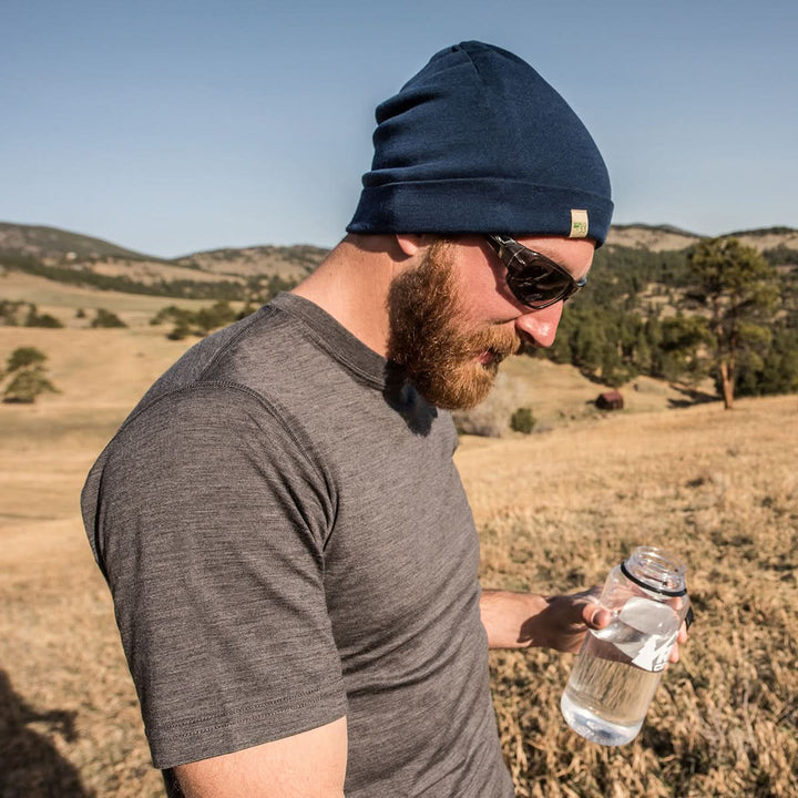 A man models a super soft, short sleeved merino wool t shirt. Use it as a base layer under your work shirt, or wear it all by itself during your next summer summit, front three-quarter view outdoors 