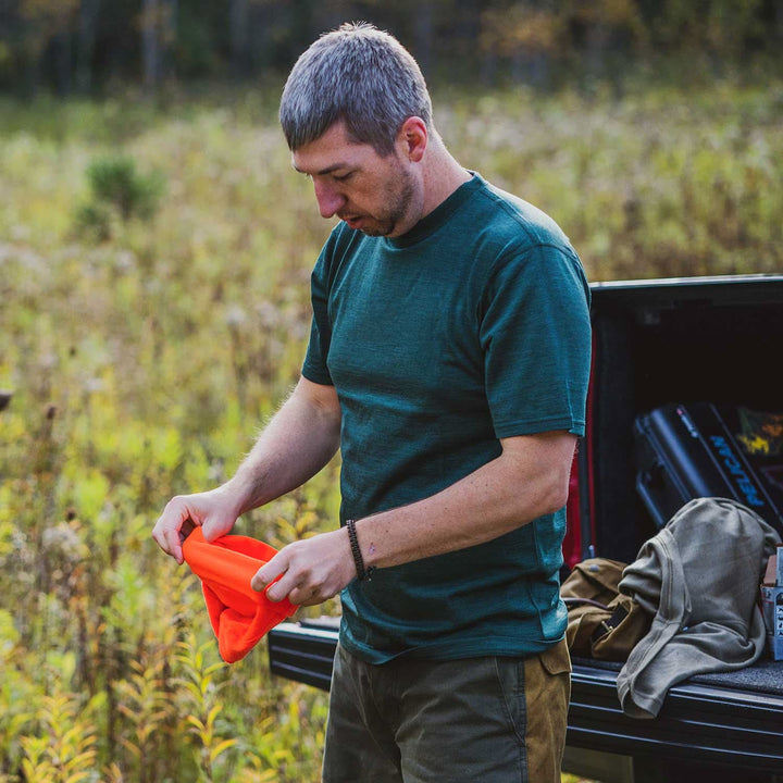A man models a super soft, short sleeved merino wool t shirt. Use it as a base layer under your work shirt, or wear it all by itself during your next summer summit, front view while hunting 