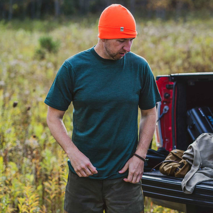 A man models a super soft, short sleeved merino wool t shirt. Use it as a base layer under your work shirt, or wear it all by itself during your next summer summit, front three-quarter view outdoors 