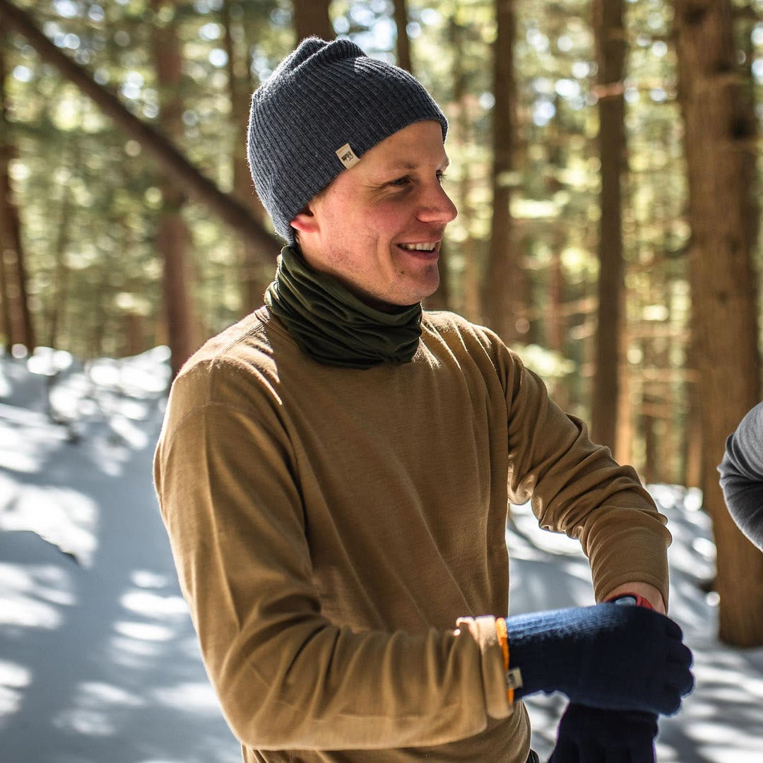 A man models a super soft, long sleeved merino wool thermal base layer crew. This top makes for a perfect first layer on a winter hike, or a nice casual wear on the chilly days of autumn and spring, front view outdoors 