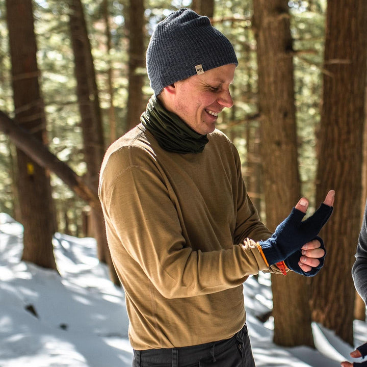 A man models a super soft, long sleeved merino wool thermal base layer crew. This top makes for a perfect first layer on a winter hike, or a nice casual wear on the chilly days of autumn and spring, front three-quarter view outdoors 