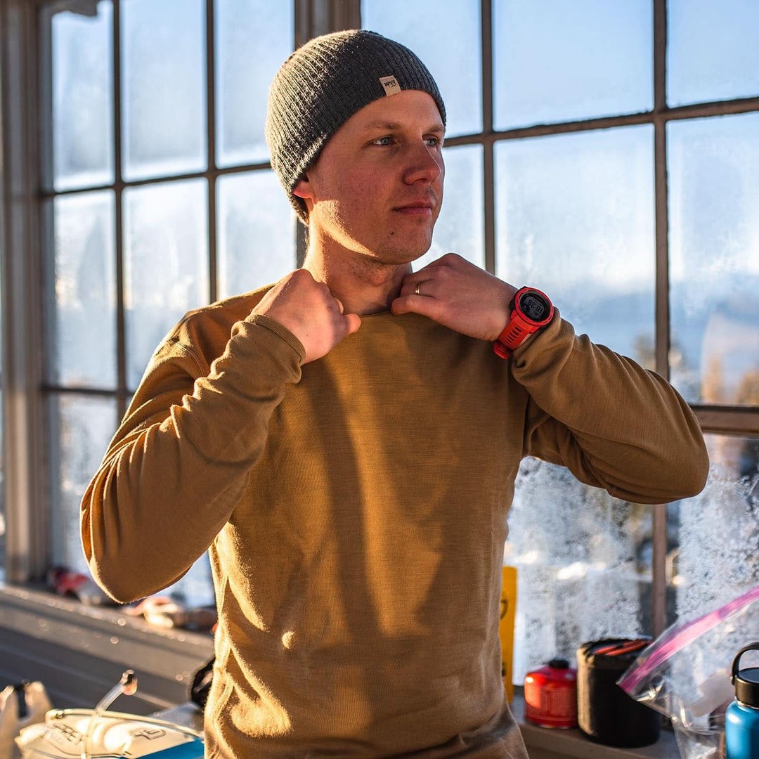 A man models a super soft, long sleeved merino wool thermal base layer crew. This top makes for a perfect first layer on a winter hike, or a nice casual wear on the chilly days of autumn and spring, right-facing side view outdoors 