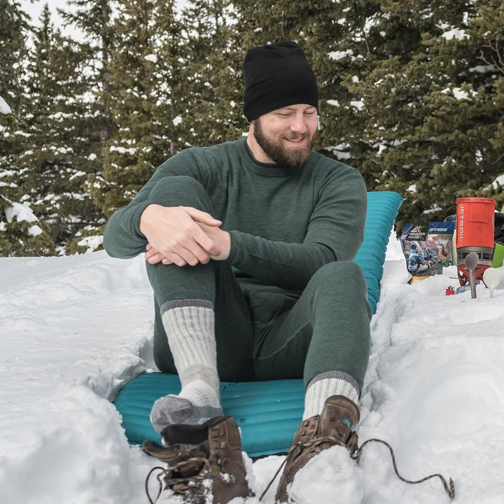 A man models a super soft, long sleeved merino wool thermal base layer crew. This top makes for a perfect first layer on a winter hike, or a nice casual wear on the chilly days of autumn and spring, front three-quarter view 