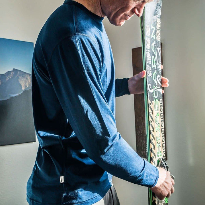 A man models a super soft, long sleeved merino wool thermal base layer crew. This top makes for a perfect first layer on a winter hike, or a nice casual wear on the chilly days of autumn and spring, front three-quarter view 