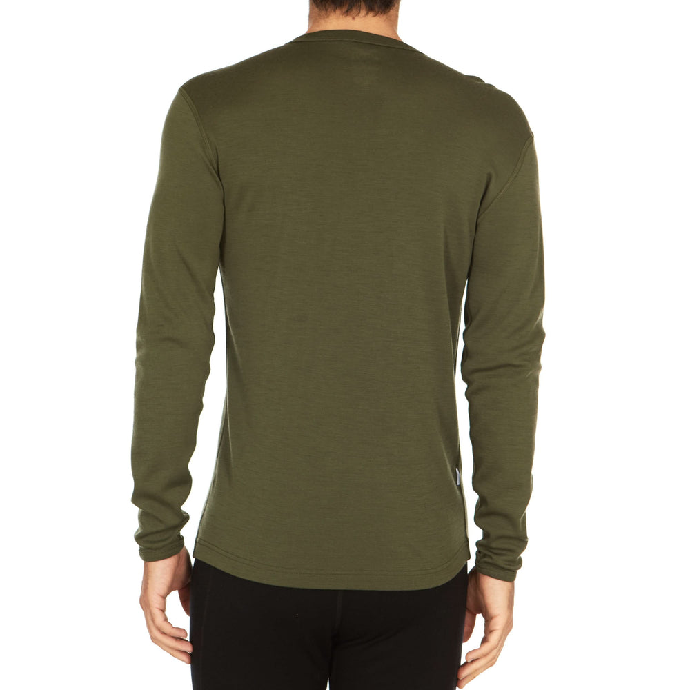 A man models a super soft, long sleeved merino wool thermal base layer crew. This top makes for a perfect first layer on a winter hike, or a nice casual wear on the chilly days of autumn and spring, back view #color_olive-drab-green