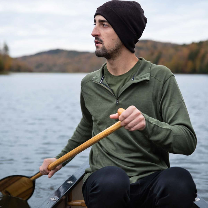 A man models the merino wool midweight quarter zip sweater, complete with flat-lock seams and thumbholes, close-up of the product rear three-quarter view 