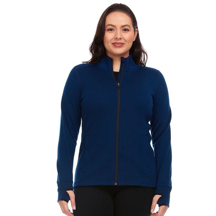 A woman models a hundred percent merino wool heavyweight full zip sweater. This outer layer features a two and a half inch mock neck collar, two zippered pockets, and thumbholes. Front view 1. 