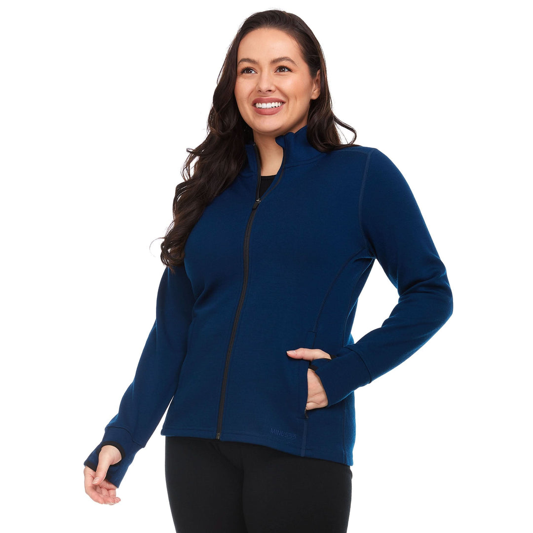 Front three-quarter view of a female model wearing a navy heavyweight merino wool full-zip sweater with mock neck, zip pockets, and thumbholes 