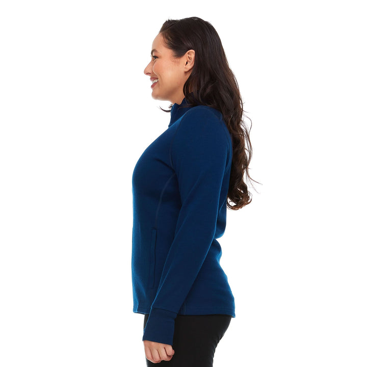 A woman models a hundred percent merino wool heavyweight full zip sweater. This outer layer features a two and a half inch mock neck collar, two zippered pockets, and thumbholes. 