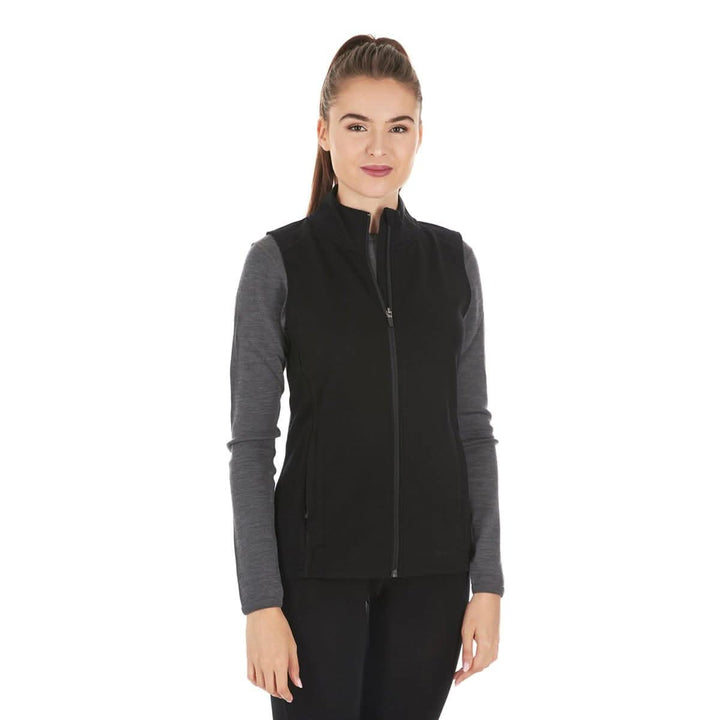 A woman models a hundred percent merino wool heavyweight full zip vest. This outer layer features a two and a half inch mock neck collar and two zippered pockets. 