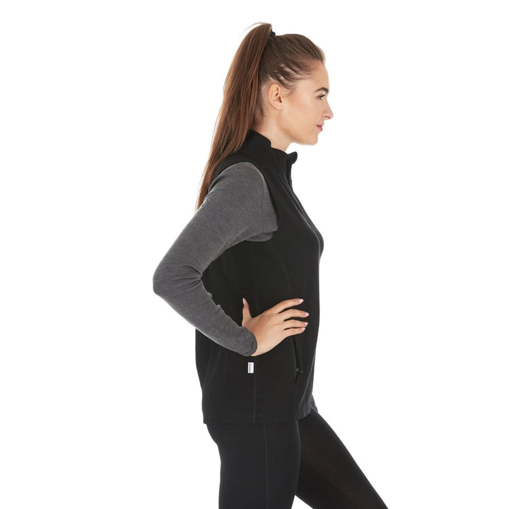 A woman models a hundred percent merino wool heavyweight full zip vest. This outer layer features a two and a half inch mock neck collar and two zippered pockets., right-facing side view 