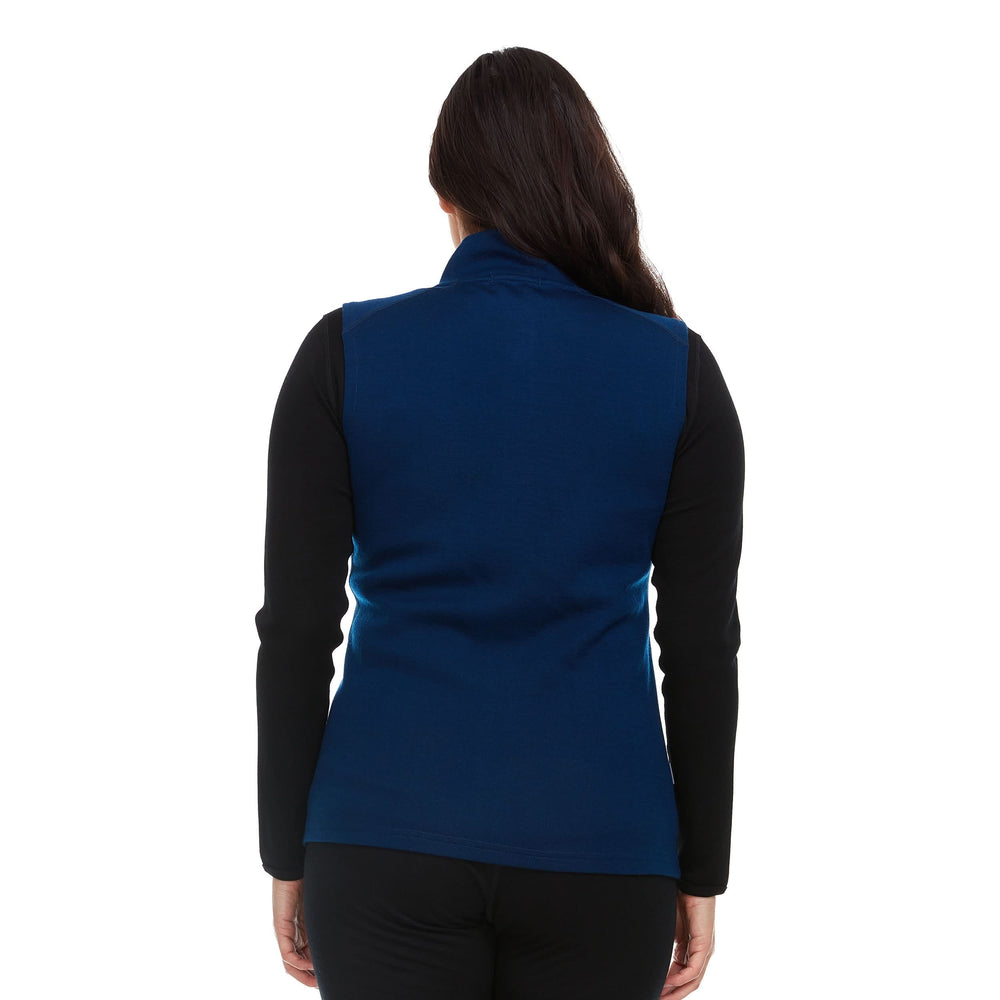 A woman models a hundred percent merino wool heavyweight full zip vest. This outer layer features a two and a half inch mock neck collar and two zippered pockets. Back view. #color_navy