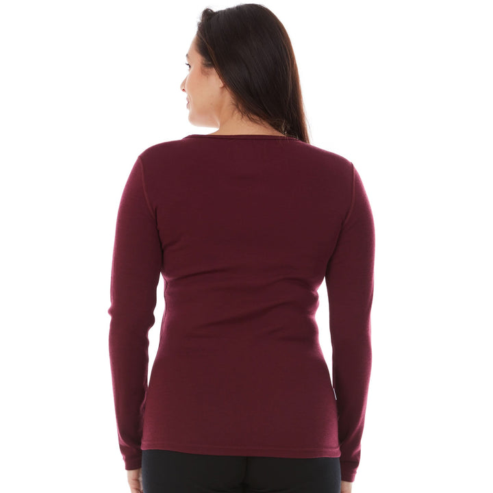 A woman models a soft, 100% merino wool, midweight base layer crew top. The women&