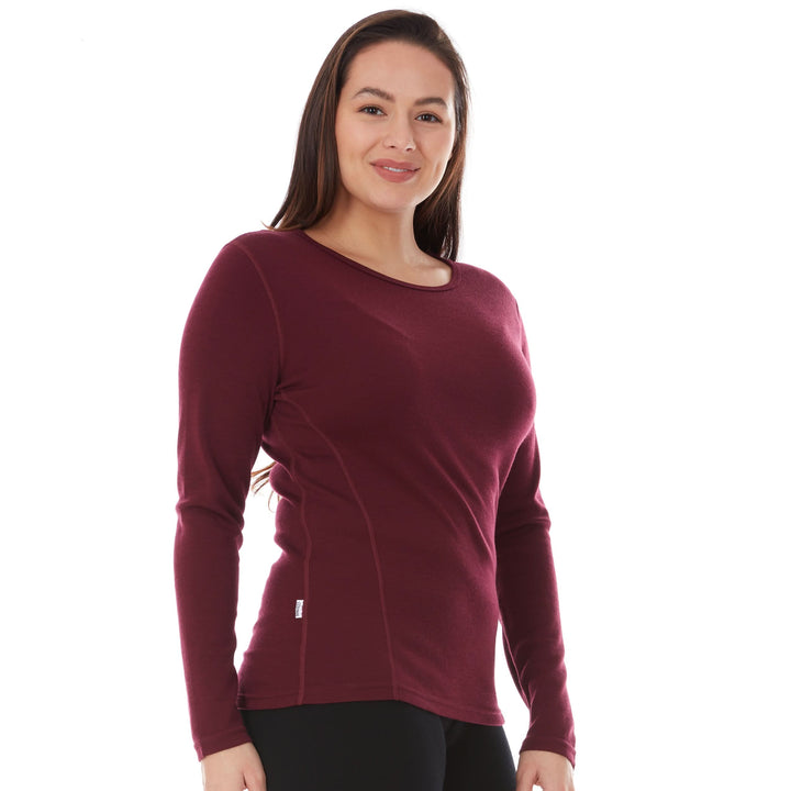A woman models a soft, 100% merino wool, midweight base layer crew top. The women&