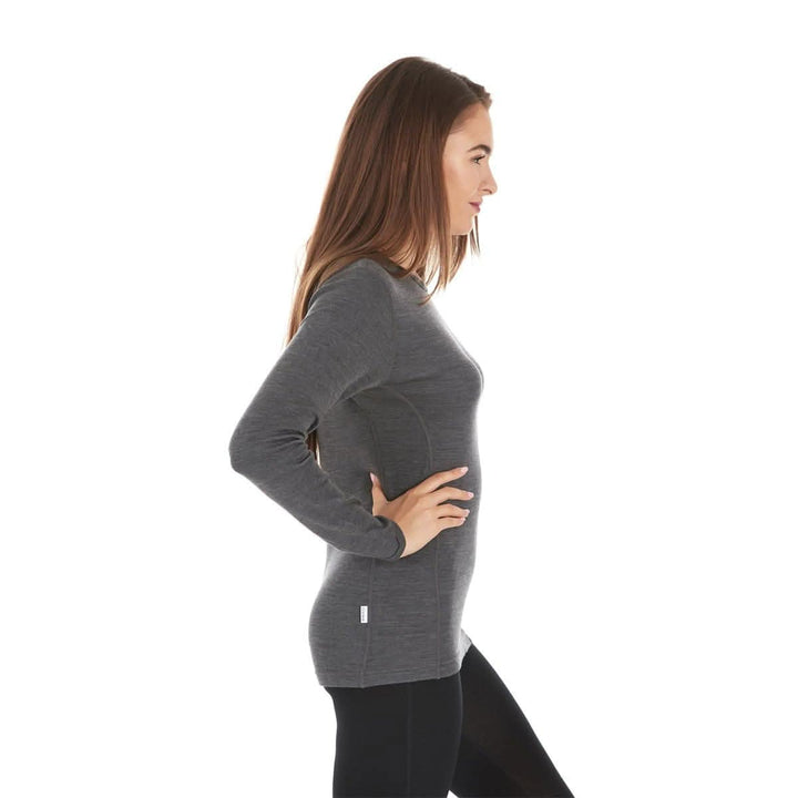 A woman models a soft, 100% merino wool, midweight base layer crew top. The women&