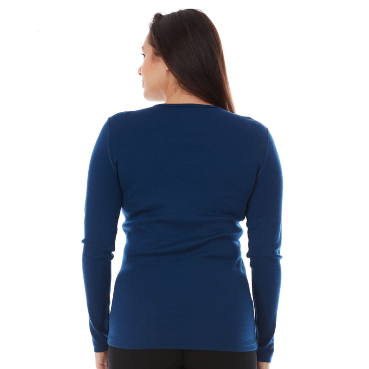 A woman models a soft, 100% merino wool, midweight base layer crew top. The women&