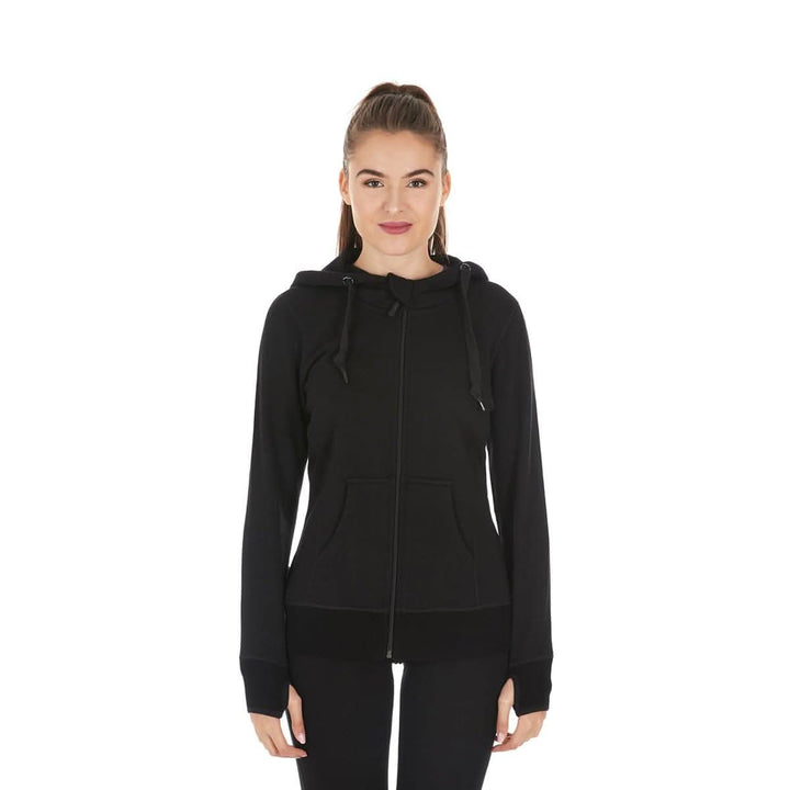 A woman models the heavyweight merino wool brushed fleece hoodie. The hoodie features a large hood with drawstrings, thumbholes, two pockets, and an interior stash pocket inside, front view 