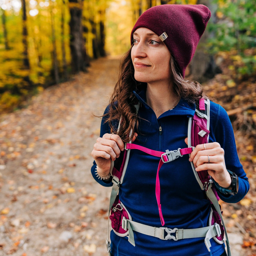 A woman wears a hiking backpack over her one hundred percent merino wool midweight quarter zip sweater with thumbholes 