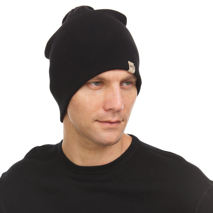 A man models a heavyweight, super soft, one hundred percent merino wool beanie. This heavyweight beanie is the warmest hat that we offer, perfect for hiking through the White Mountains, or sitting at a bonfire in January. 