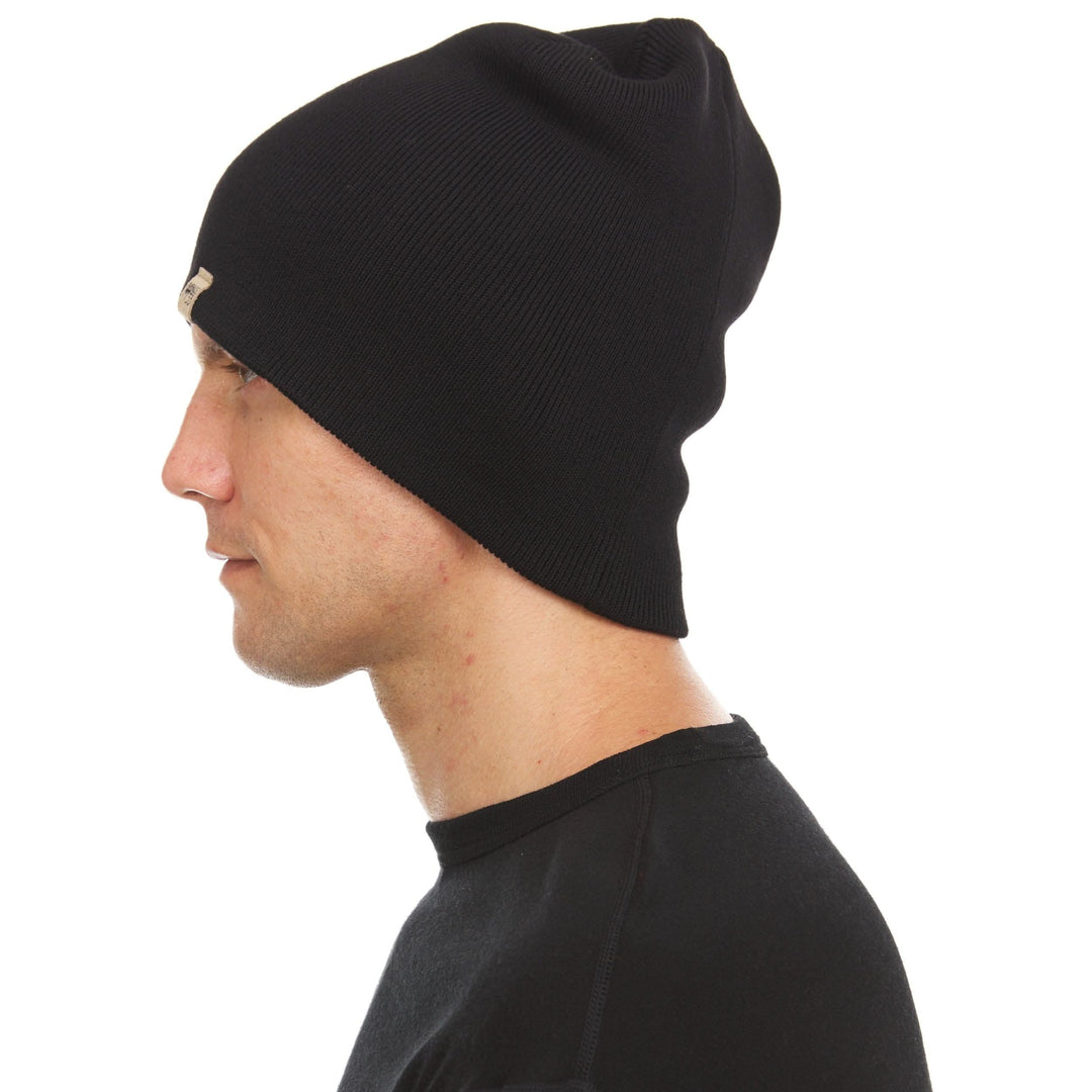 A man models a heavyweight, super soft, one hundred percent merino wool beanie. This heavyweight beanie is the warmest hat that we offer, perfect for hiking through the White Mountains, or sitting at a bonfire in January. 