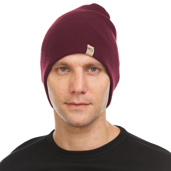 A man models a heavyweight, super soft, one hundred percent merino wool beanie. This heavyweight beanie is the warmest hat that we offer, perfect for hiking through the White Mountains, or sitting at a bonfire in January. 
