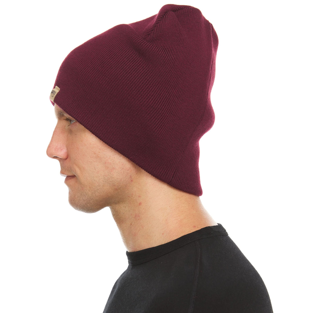 A man models a heavyweight, super soft, one hundred percent merino wool beanie. This heavyweight beanie is the warmest hat that we offer, perfect for hiking through the White Mountains, or sitting at a bonfire in January., right-facing side view 