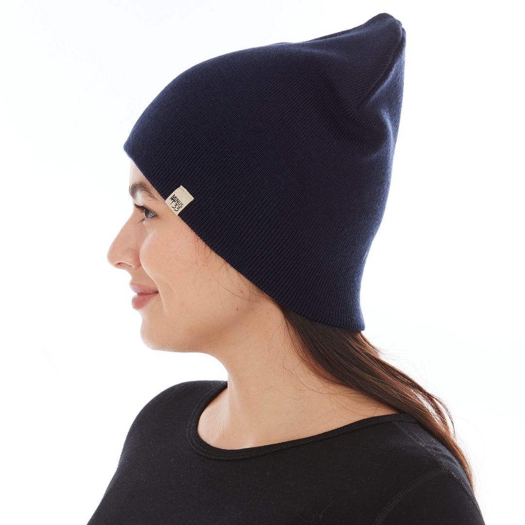 A woman models a heavyweight, super soft, one hundred percent merino wool beanie. This heavyweight beanie is the warmest hat that we offer, perfect for hiking through the White Mountains, or sitting at a bonfire in January, right-facing side view 