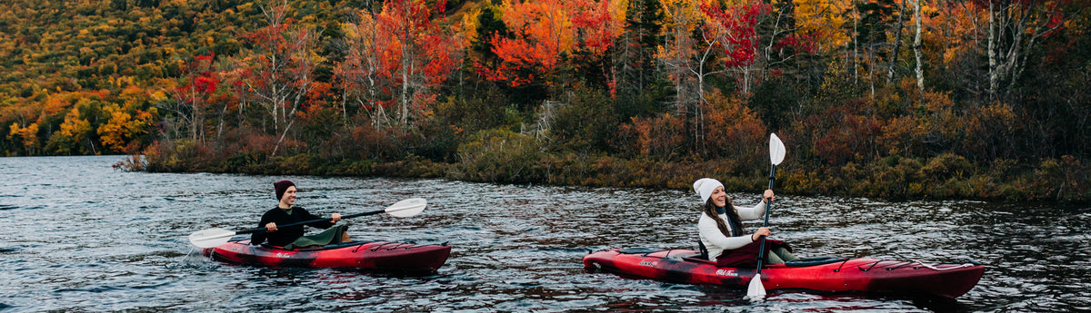 Photo of Man and woman kayaking on a pond surrounded by fall foliage wearing Merino wool 