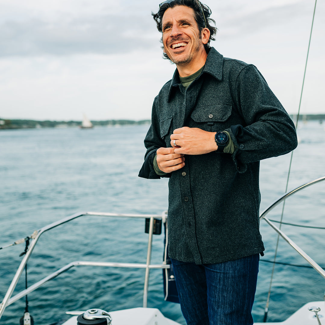 Man buttons heavy wool shirt jac while sailing 
