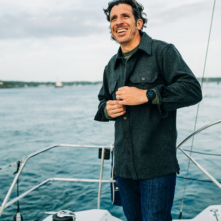 Man buttons heavy wool shirt jac while sailing 