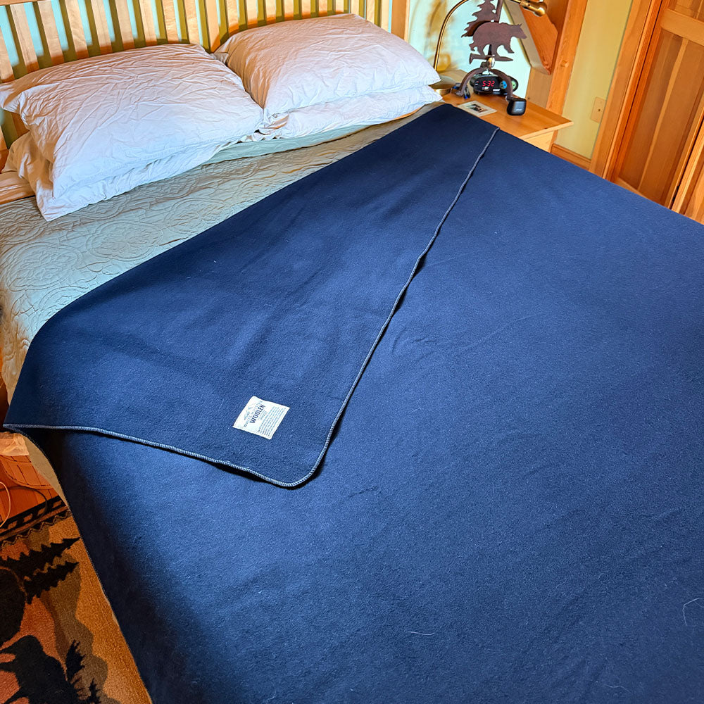 King merino blanket spread across a wooden bed with label 