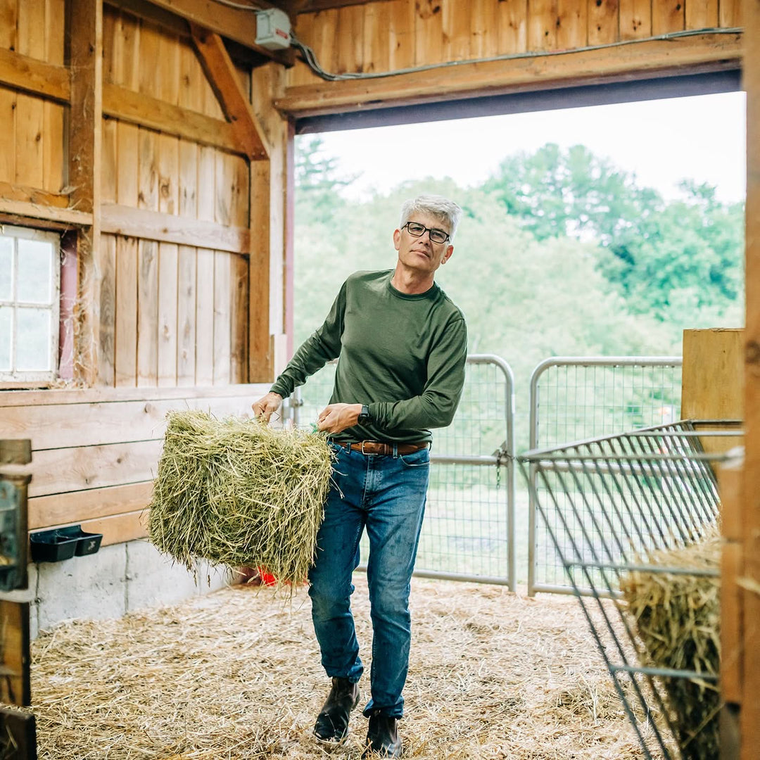 Man carries hay bale into barn 
