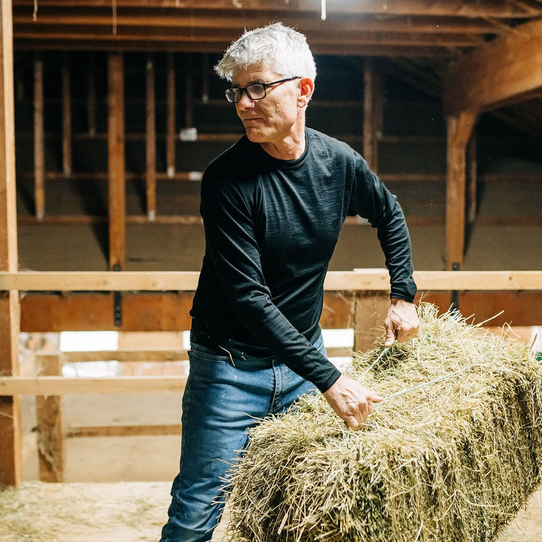 Man throws hay bale in barn 