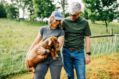 couple holding a baby sheep in merino wool t shirt and wool shirt crew