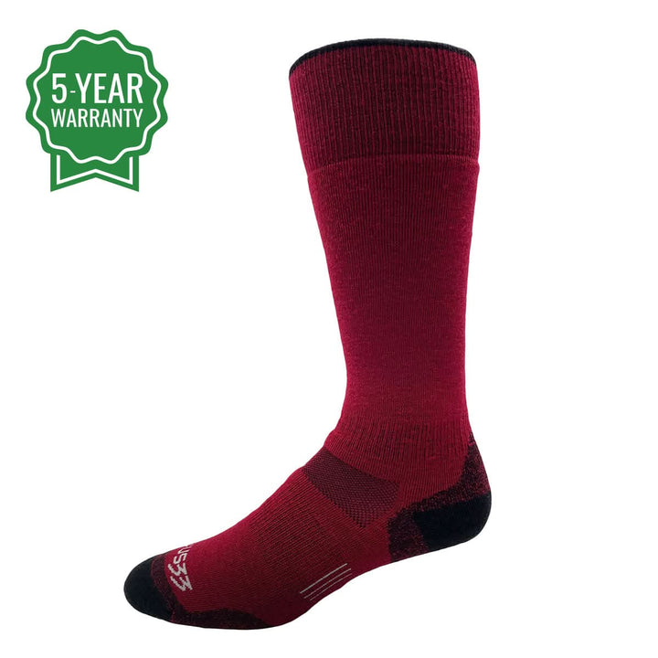 Three-quarter side view of a true-red lightweight over-the-calf merino wool sock with black toe and heel reinforcement, ribbed cuff, arch support panel, and a green 5-year warranty badge 
