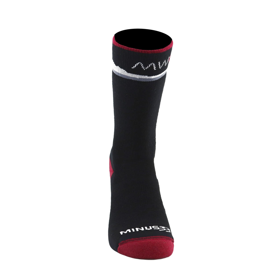 Front three-quarter view of a black merino wool crew sock with a red toe, heel, and cuff trim, white mountain-line pattern, and Minus33 logo