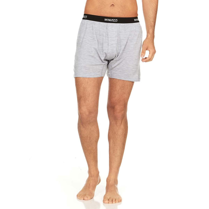 Front view from waist to mid-thigh of a man wearing ash gray Woolverino micro weight merino wool boxer shorts, showing the elastic waistband, button fly, relaxed cut, and loose leg openings 