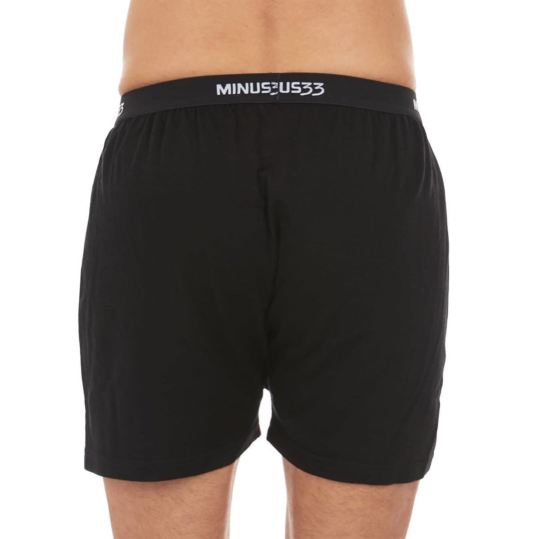 Back close-up from waist to mid-thigh of a man wearing black Woolverino micro weight merino wool boxer shorts, showing the elastic waistband, smooth rear panel, relaxed fit, and loose leg openings 
