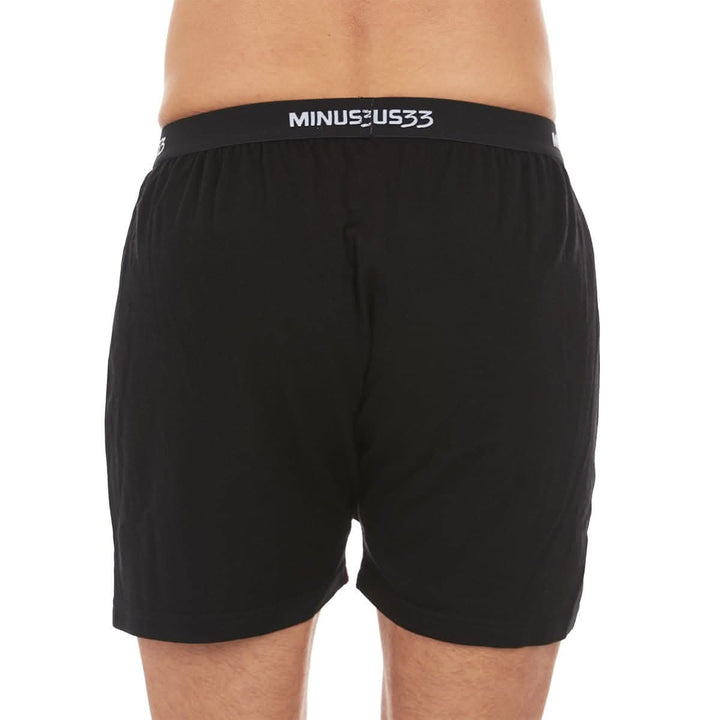 Back close-up from waist to mid-thigh of a man wearing black Woolverino micro weight merino wool boxer shorts, showing the elastic waistband, smooth rear panel, relaxed fit, and loose leg openings 