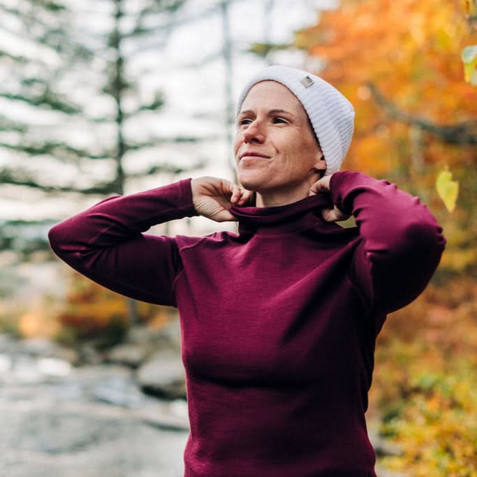 Woman wearing a burgundy merino wool turtleneck and white beanie outdoors in autumn 