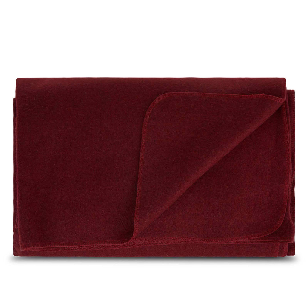 Front view of a folded burgundy lodge wool blanket with the upper-right corner turned down, revealing the matching reverse surface and softly rounded stitched binding 