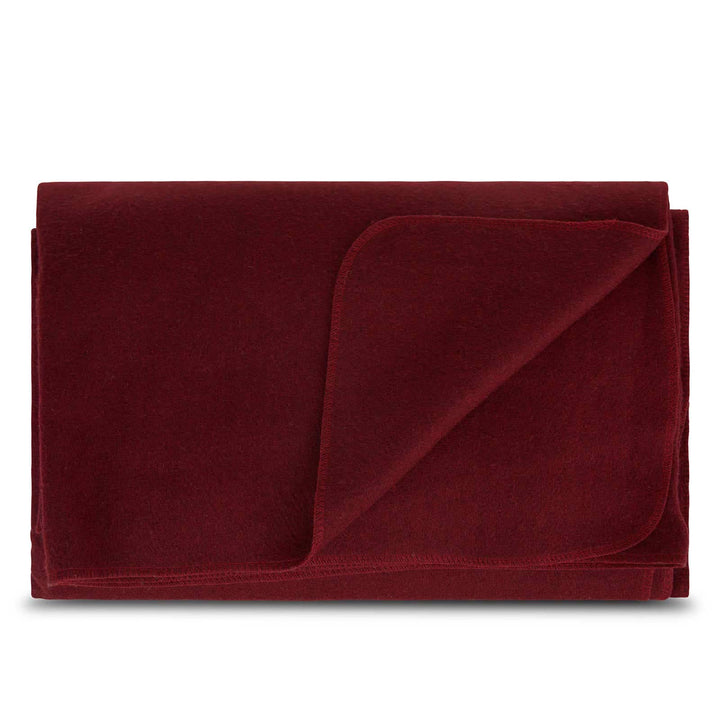Front view of a folded burgundy lodge wool blanket with the upper-right corner turned down, revealing the matching reverse surface and softly rounded stitched binding 
