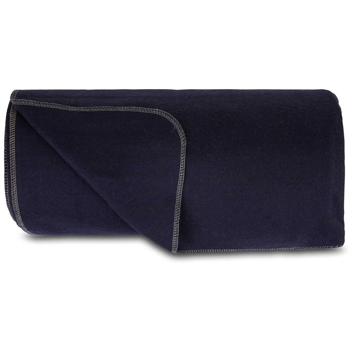 Front view of a solid navy lodge wool blanket folded lengthwise into a low roll, with one rounded corner opened to show the matching reverse side and light contrast stitching 