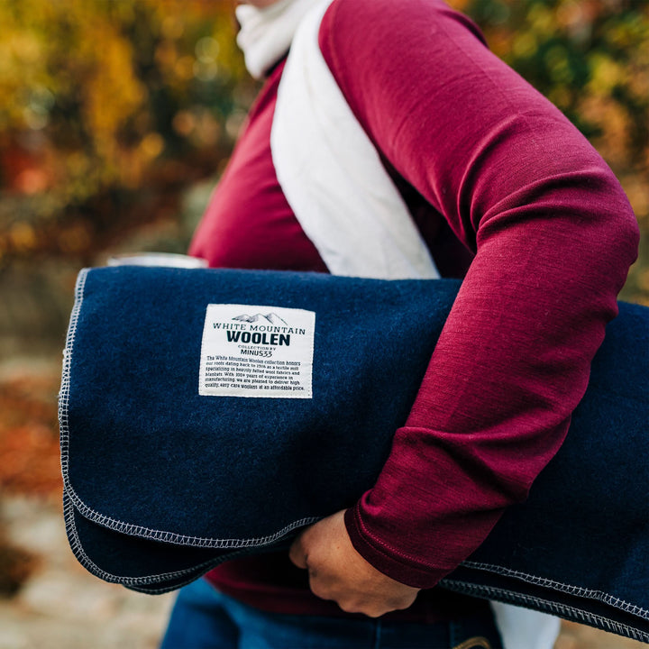 Lodge twin wool blanket, woman carrying the folded blanket with label visible 