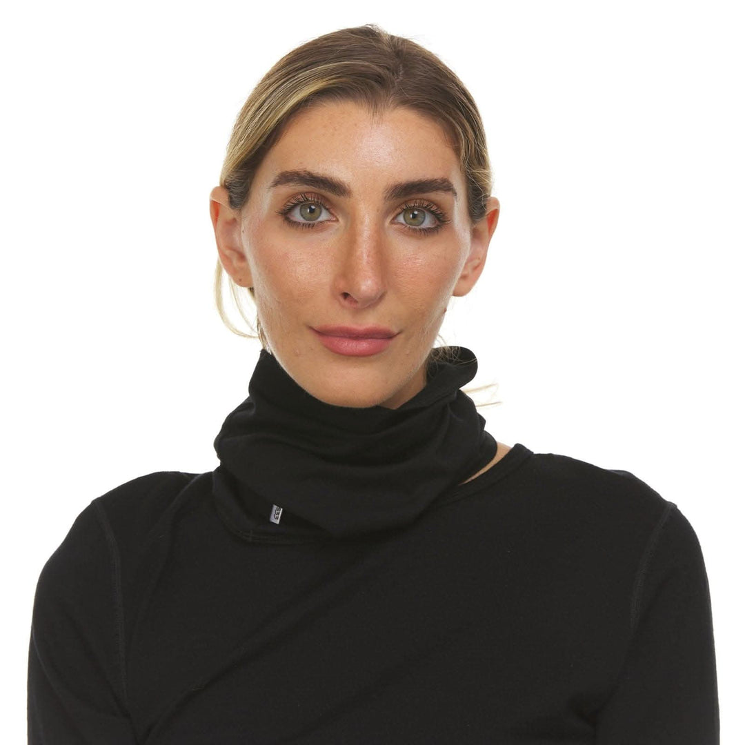 Side view of a person wearing a black Woolverino micro weight merino wool half neck gaiter, showing the tubular fabric covering the neck and lower face, smooth stretch knit, and folded lower edge