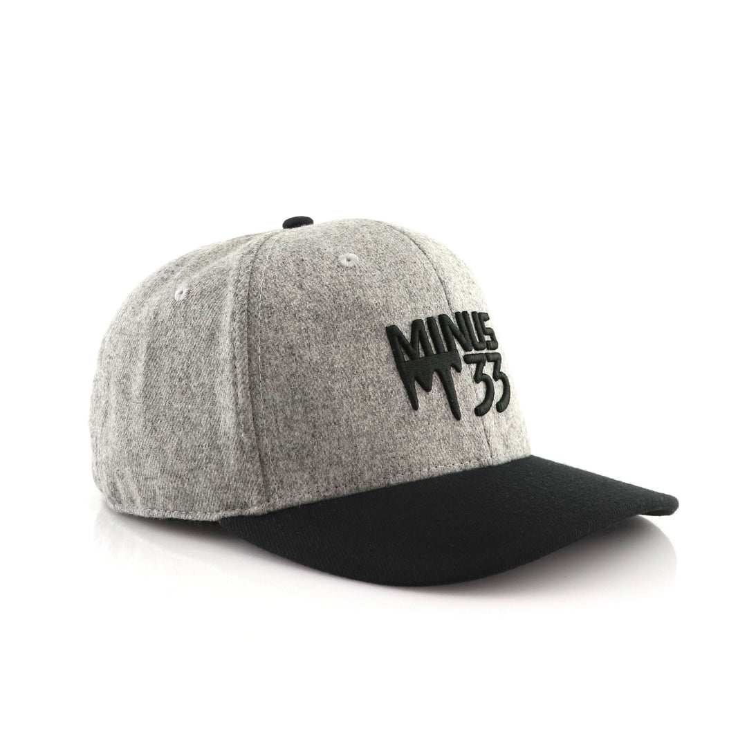 Three-quarter front view of a gray heather baseball cap with a curved bill, structured crown, embroidered green M33 mountain logo, and visible top button and panel seams 