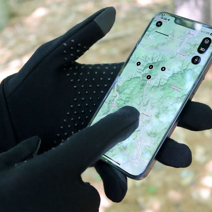 Man wearing black Merino touchscreen gloves with no slip dots scrolls map on phone 