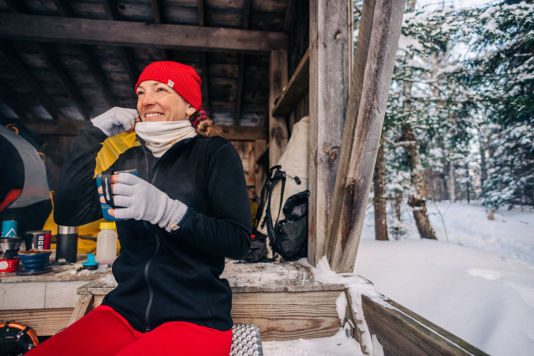 women sitting down drinking coffee ontop of a mountain in merino wool expedition full zip sweater