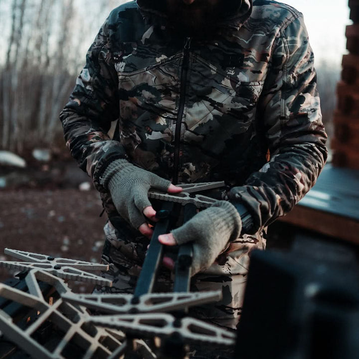 Hunter loads a crossbow wearing fingerless merino gloves 