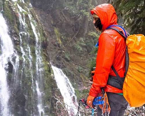 man next to waterfall in the rain wearing merino wool beanie and jacket
